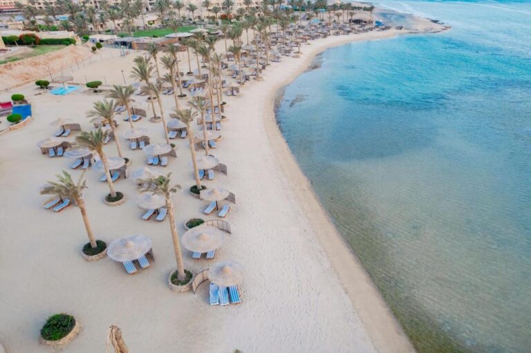 Luchtfoto van het strand van het Blend Elphistone Resort, met palmbomen, strooien parasols en de turquoise zee