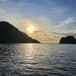 Het Cocoseiland in tegenlicht bij zonsondergang, met rechts een liveaboard voor anker, op een kalme zee