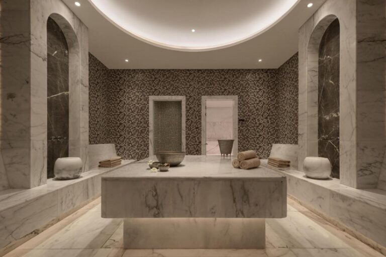 Een ruimte in de spa van het JAZ Elite Riviera, bekleed met marmer, met een brede stenen tafel in het midden