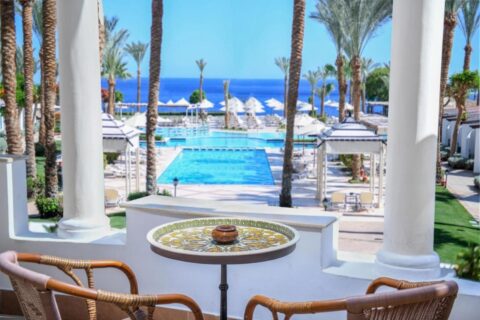 Het uitzicht vanaf een terras van het JAZ Fanara Resort op de zwembaden, de palmbomen en de Rode Zee