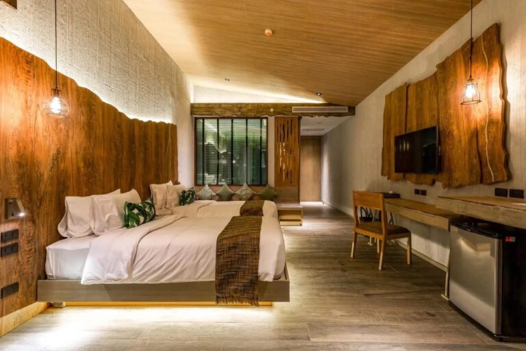 Een kamer met twee bedden, een hoofdeinde van ruw hout, een bureau en een tv