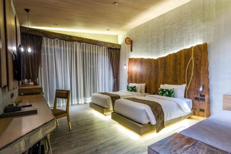 Een kamer met twee bedden met verlichting eronder, een bureau en vitrages