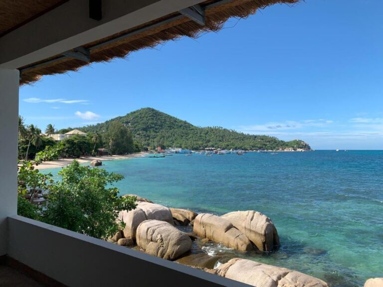 De baai en de rotsen gezien vanaf een overdekt terras van het Koh Tao Heritage, met boten voor anker