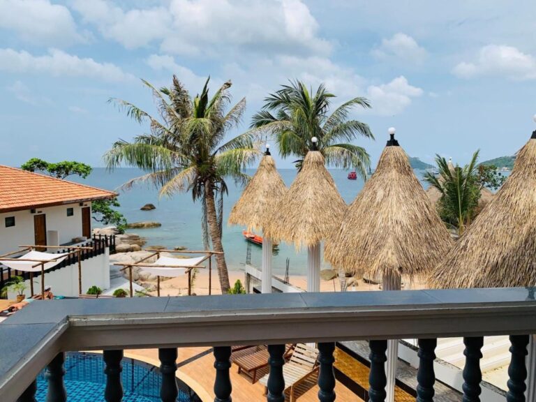 Uitzicht vanaf een balkon op de strooien parasols, de palmbomen en de zee