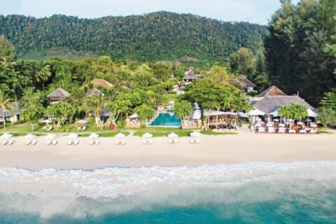 Het Layana Resort gezien vanaf zee, met het strand, de witte parasols, het zwembad en de daken onder de palmbomen