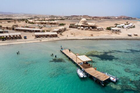 Luchtfoto van Marsa Shagra Village, met de steiger, twee zodiacs en het dorp aan het turquoise water