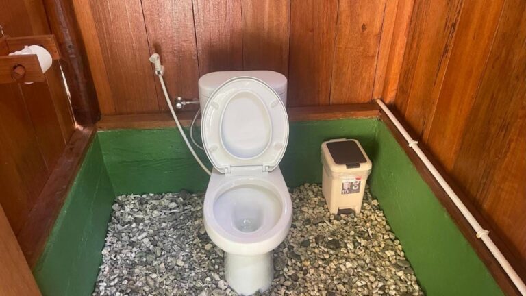 Een toilet met houten wanden en een vloer van kiezels