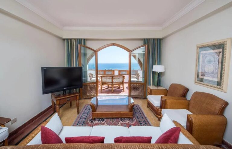 Een zitkamer die via een boogdeur uitkomt op een terras met uitzicht op zee