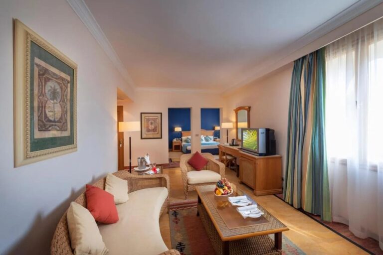 Een zitkamer met rotan meubels, met achterin een slaapkamer met een blauwe muur
