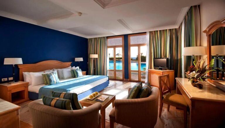 Een kamer met een tweepersoonsbed, een blauwe muur en openslaande deuren naar het zwembad