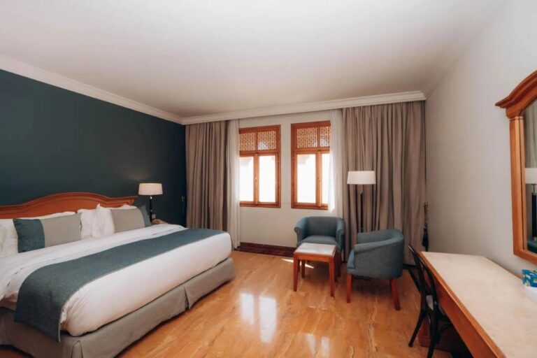 Een kamer met een tweepersoonsbed, een donkergroene muur en twee blauwe fauteuils