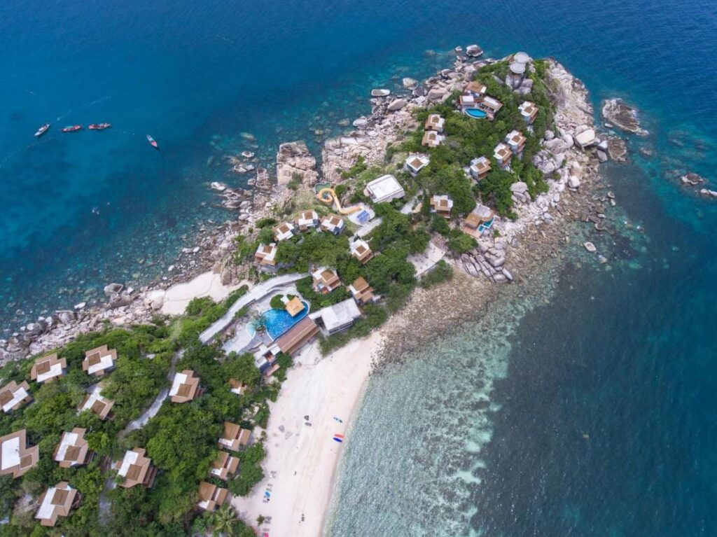 Luchtfoto van het Sai Daeng Resort, met zijn bungalows op een rotsachtige landtong, zijn zwembaden en zijn zandstrand
