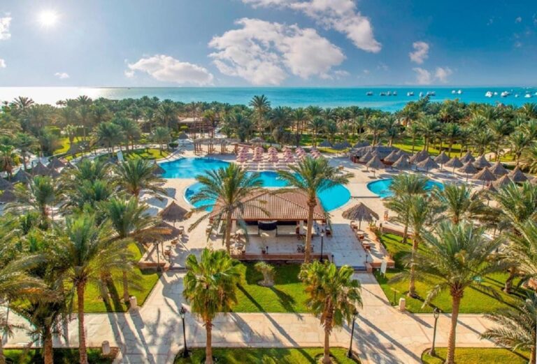Luchtfoto van het Siva Grand Beach, met zijn zwembaden tussen de palmbomen en de Rode Zee met boten voor anker